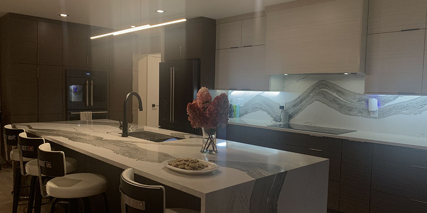 Modern kitchen with light gray cabinetry, a large island with seating, and stainless steel appliances.