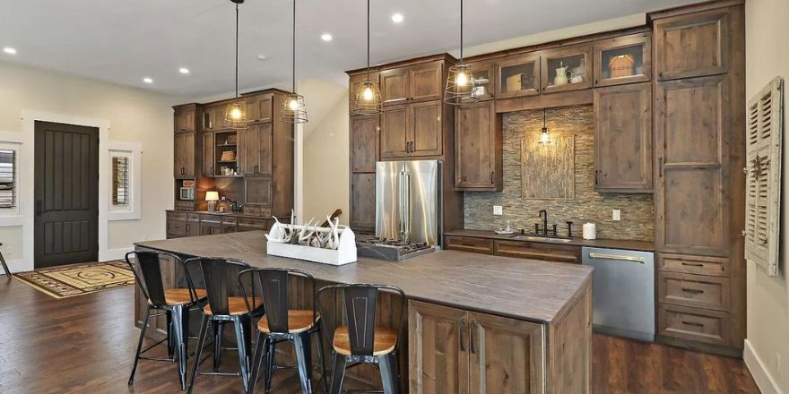 A bright kitchen with white cabinetry, a large marble island, and stainless steel appliances.
