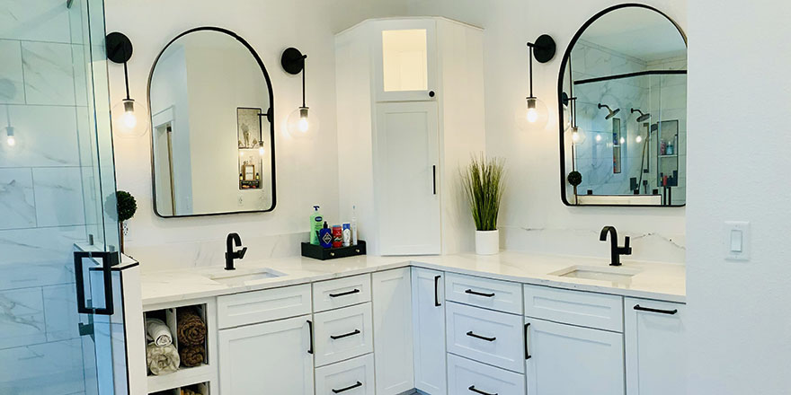 Bright kitchen with white and dark green cabinetry, featuring a farmhouse sink, stainless steel refrigerator, and a marble-like countertop.