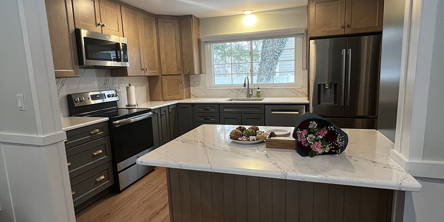 Modern kitchen with light gray cabinetry, a large island with seating, and stainless steel appliances.