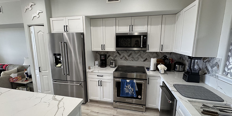 Modern kitchen with light gray cabinetry, a large island with seating, and stainless steel appliances.