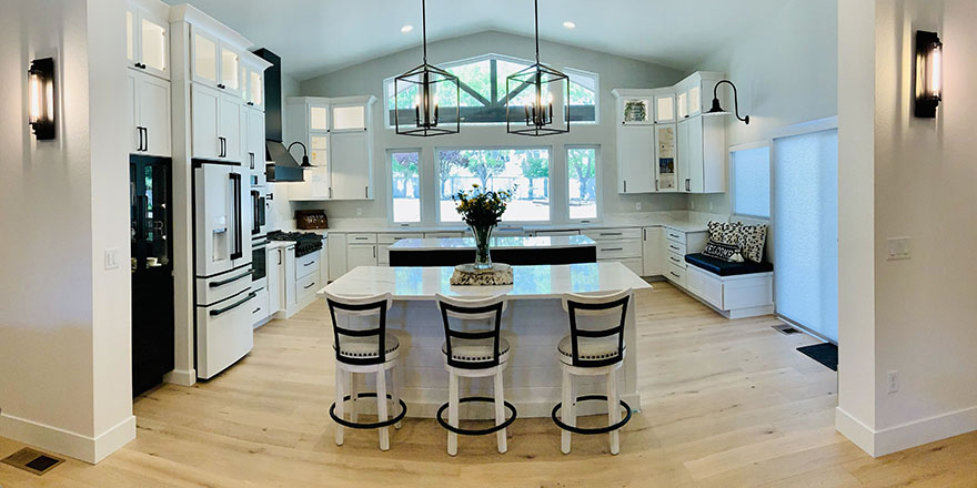 Bright kitchen with white and dark green cabinetry, featuring a farmhouse sink, stainless steel refrigerator, and a marble-like countertop.