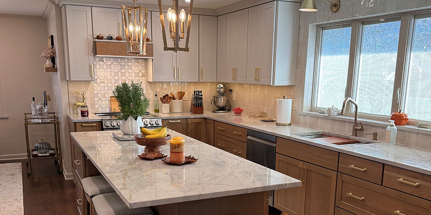 Modern kitchen with light gray cabinetry, a large island with seating, and stainless steel appliances.