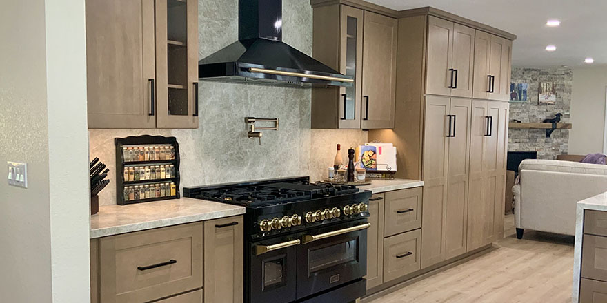 Bright kitchen with white and dark green cabinetry, featuring a farmhouse sink, stainless steel refrigerator, and a marble-like countertop.