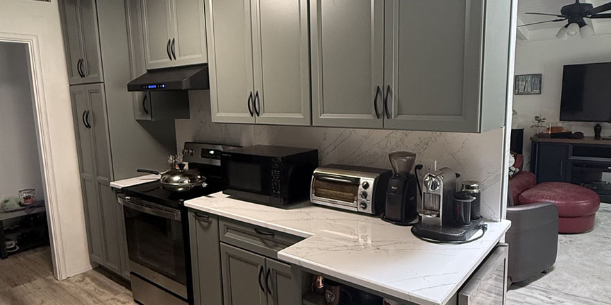 Modern kitchen with navy blue cabinetry, stainless steel appliances, and a sink.