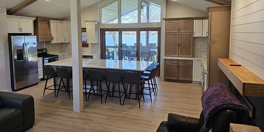 Modern kitchen with light gray cabinetry, a large island with seating, and stainless steel appliances.