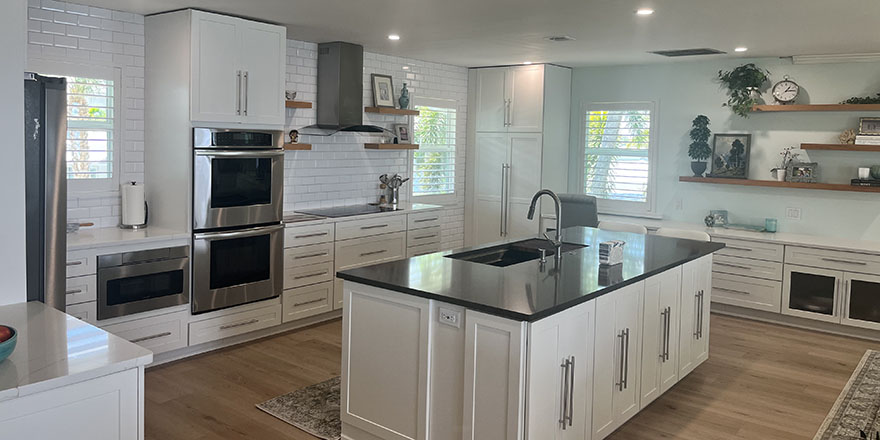 Bright kitchen with white cabinetry, a stainless steel refrigerator, and a coffee station beside the microwave.