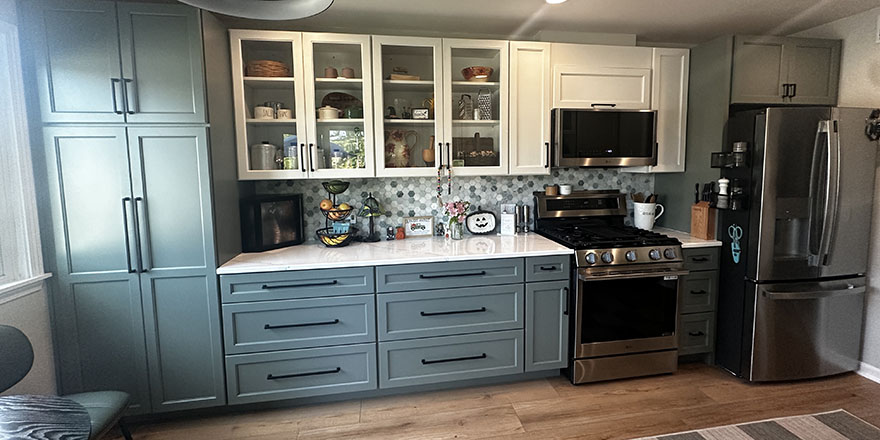 Modern kitchen with light gray cabinetry, a large island with seating, and stainless steel appliances.