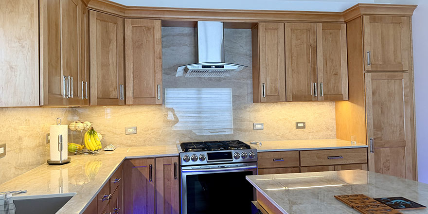 A bright kitchen with white cabinetry, a large marble island, and stainless steel appliances.