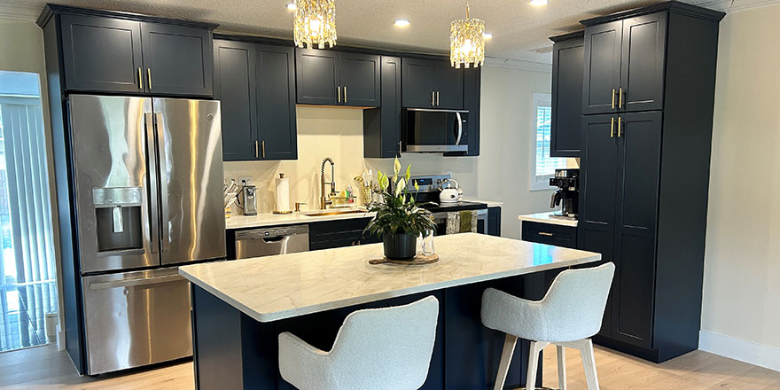 Bright kitchen with white and dark green cabinetry, featuring a farmhouse sink, stainless steel refrigerator, and a marble-like countertop.