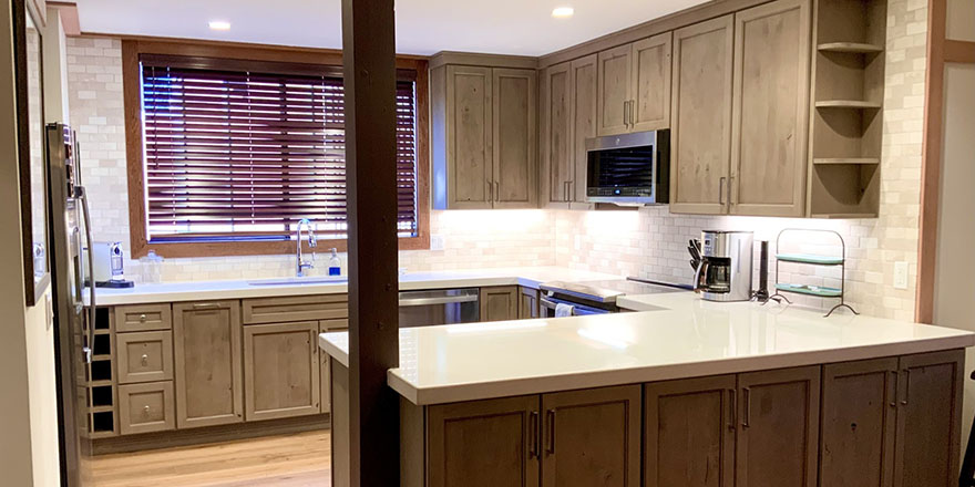 Modern kitchen with light gray cabinetry, a large island with seating, and stainless steel appliances.