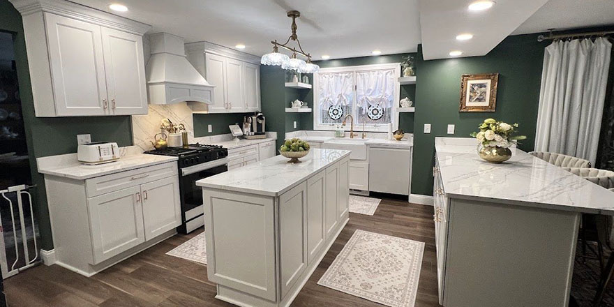 A bright kitchen with white cabinetry, a large marble island, and stainless steel appliances.