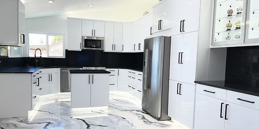 Bright kitchen with white and dark green cabinetry, featuring a farmhouse sink, stainless steel refrigerator, and a marble-like countertop.