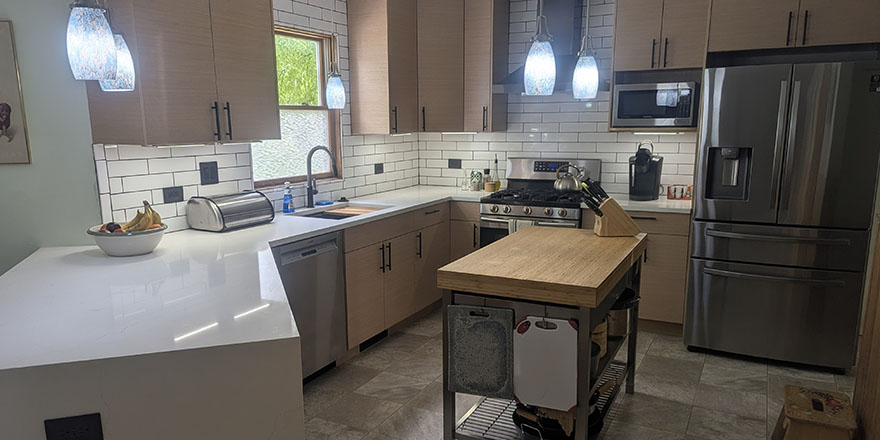 Bright kitchen with white cabinetry, a stainless steel refrigerator, and a coffee station beside the microwave.