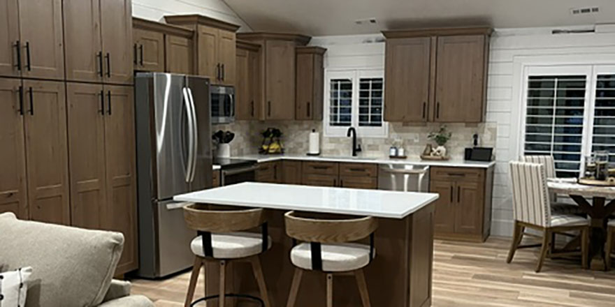 Modern kitchen with light gray cabinetry, a large island with seating, and stainless steel appliances.