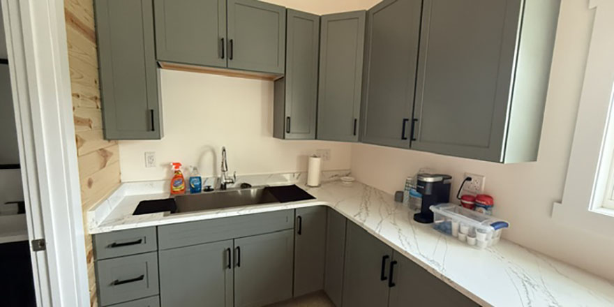 A bright kitchen with white cabinetry, a large marble island, and stainless steel appliances.