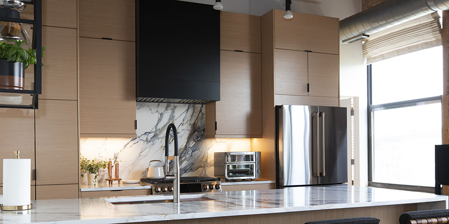 Modern kitchen with navy blue cabinetry, stainless steel appliances, and a sink.