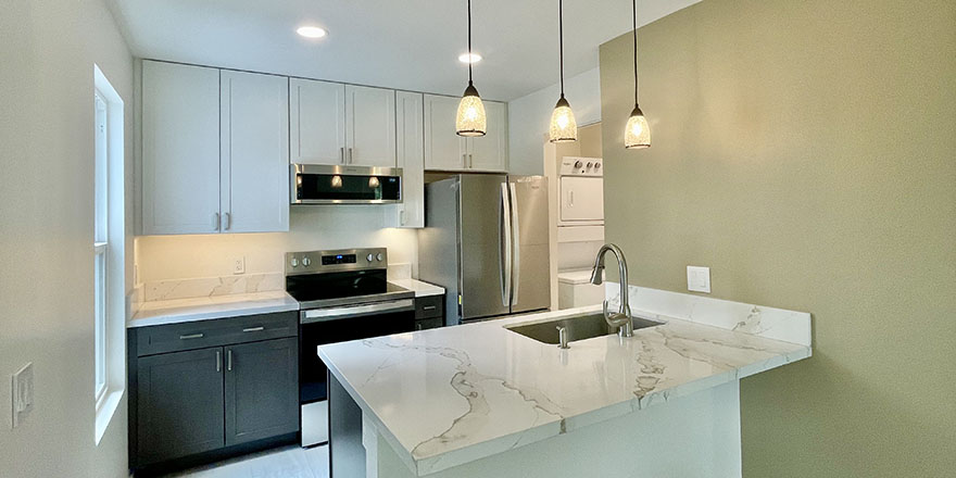 Bright kitchen with white cabinetry, a stainless steel refrigerator, and a coffee station beside the microwave.