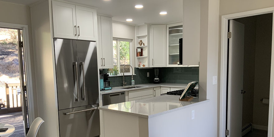 Modern kitchen with light gray cabinetry, a large island with seating, and stainless steel appliances.